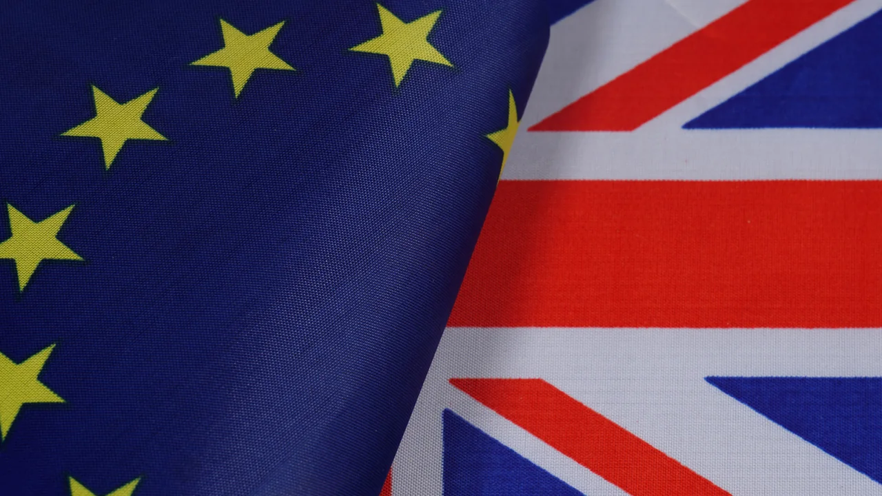 Close-up fabric EU flag with yellow stars at left and Union Jack at right. Context illustration, not a photograph of a UK accession event.