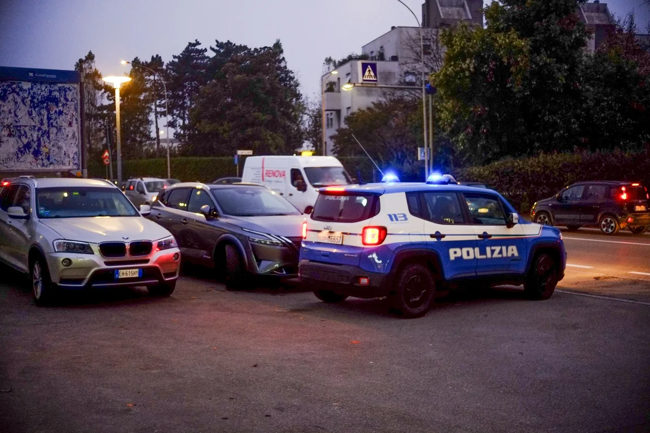 A blue and white Polizia vehicle with blue lights in dusk traffic in Traversetolo, photographed in November 2024.