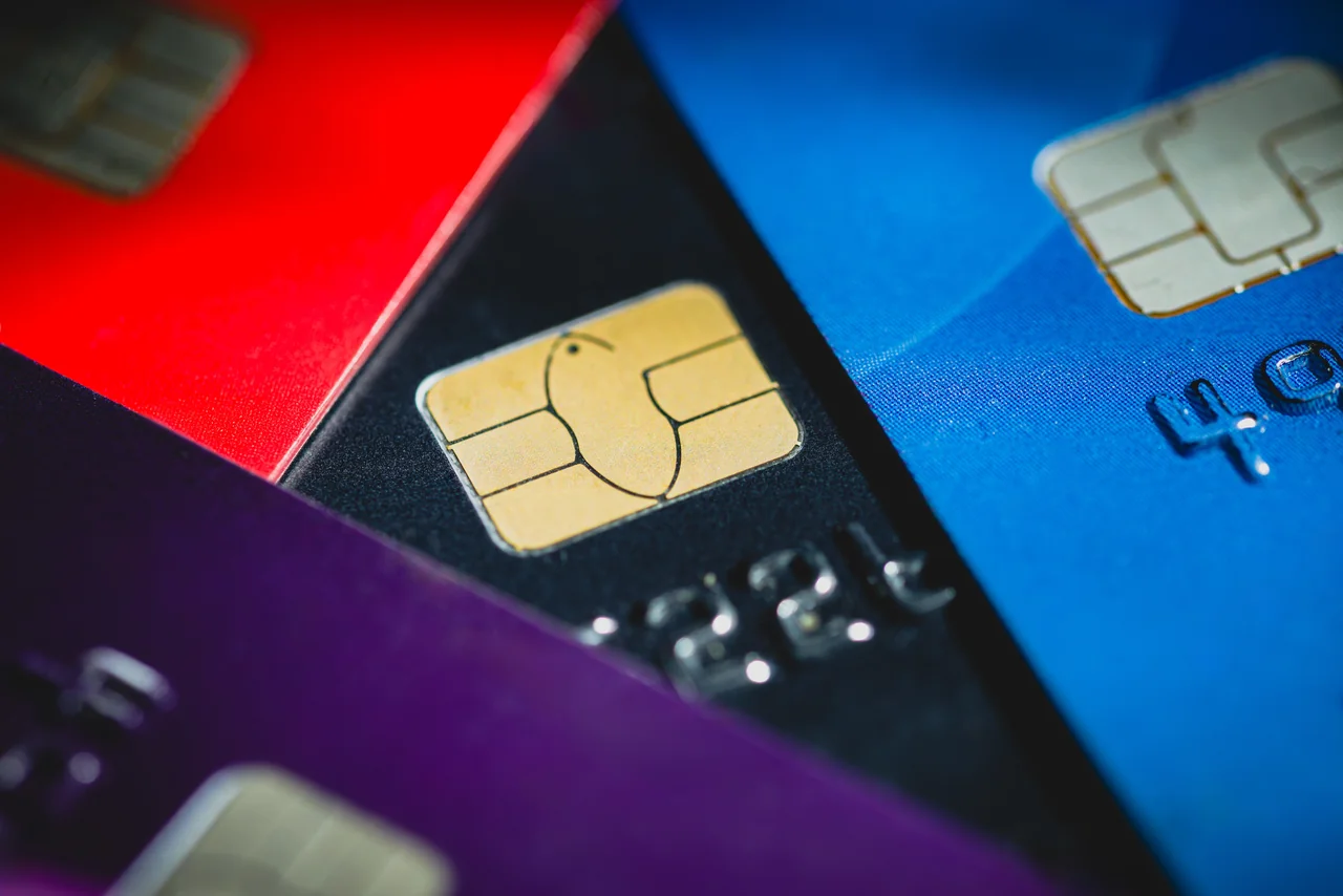 Close-up of overlapping red, black, blue and purple bank cards with chips. Generic bank-card illustration, not an accepted voter-ID specimen.